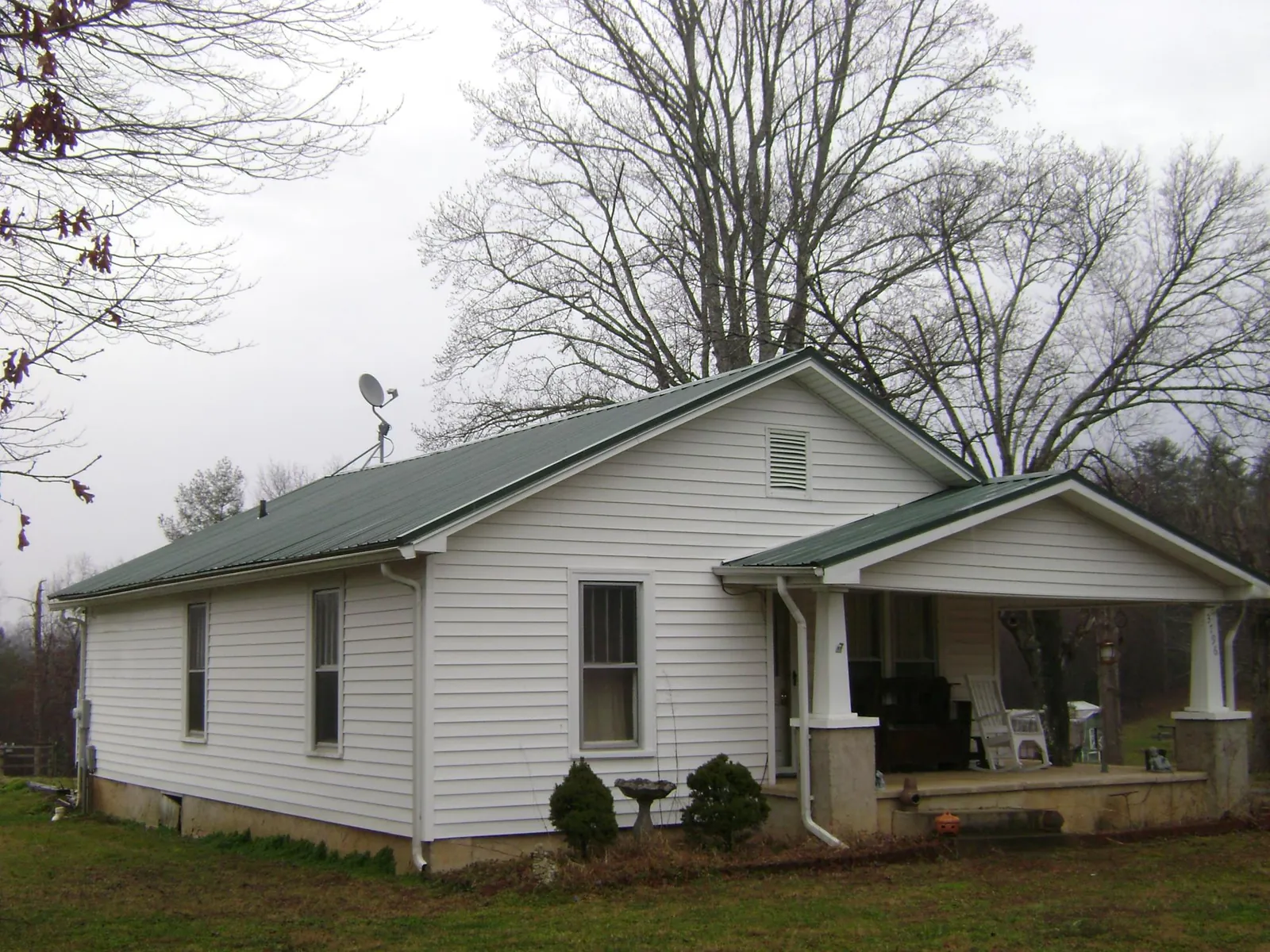 Green metal roof on a white bungalow with a side porch in Midway